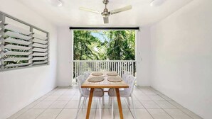 A balcony with a table and chairs, a ceiling fan, and a view of greenery. - Trinity Beach Bliss: Experience Tropical Living (Trinity Beach)