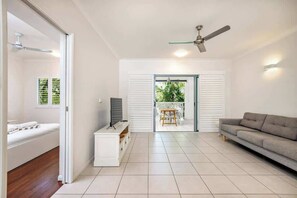 Ein modernes Wohnzimmer mit einer Couch, einem Fernseher und einem Deckenventilator.