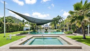 A rectangular pool with a central fountain, surrounded by a well-maintained lawn and palm trees. - Trinity Beach Bliss: Experience Tropical Living (Trinity Beach)