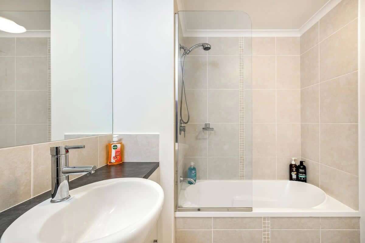 A modern bathroom with a sink, mirror, shower, and bathtub.
