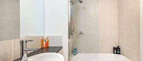 A modern bathroom with a sink, mirror, shower, and bathtub.