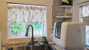 Una cocina con un lavamanos, un tostador y una ventana con un letrero que dice 'WELCOME'.