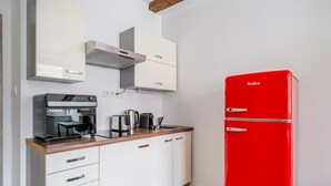 A compact kitchen with a red refrigerator, a coffee machine, and a kettle on the counter. - Blueground | Žižkov, city view, nr Vitkov Hill (PRG-95) (Prague)
