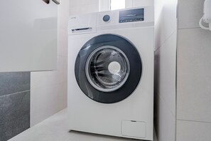 A front-loading washing machine in a modern bathroom with tiled walls and floor. - Blueground | Žižkov, view, nr Vitkov Hill (PRG-96) (Prague)