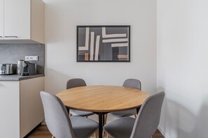 A modern kitchen with a round wooden table and four grey chairs. - Blueground | Žižkov, view, nr Vitkov Hill (PRG-96) (Prague)