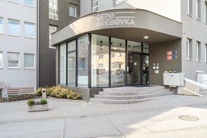 A modern building with a curved entrance, glass doors, and a sign reading 'DEPO GRÉBOVKA'. - Blueground | Vinohrady, rooftop, nr Riegrovy Sady (PRG-98) (Prague)