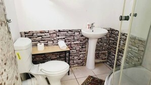 A bathroom with a toilet, sink, and shower.