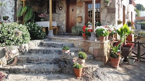 A stone building with a wooden porch, potted plants, and a small table. - Holiday Home in Vera de Erques (Guia de Isora)