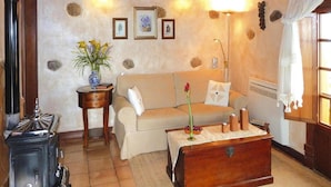 A cozy living room with a sofa, a small side table, a decorative vase, a wooden chest, and a vintage stove. - Holiday Home in Vera de Erques (Guia de Isora)