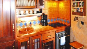 A kitchen with wooden cabinets, a sink, a stove, and a coffee maker. - Holiday Home in Vera de Erques (Guia de Isora)