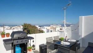 A rooftop terrace with a grill, outdoor seating, and a view of the cityscape. - Maisonette With Beautiful Terrace (Mykonos)