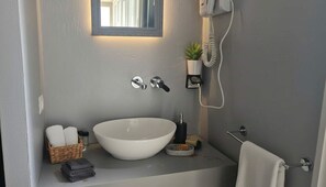 A bathroom with a white sink, a mirror, a telephone, and a small potted plant. - Maisonette With Beautiful Terrace (Mykonos)