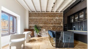 Een moderne keuken met een stenen muur, houten vloer en een bar met krukken.