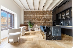A modern kitchen with a stone wall, wooden flooring, and a bar area with stools. - Luxurious, brand new apt Piazza del Popolo 4bedroom and 4bathroom in historic building (Roma)