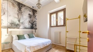 Een slaapkamer met een bed, een radiator, een raam en een kunstwerk aan de muur.