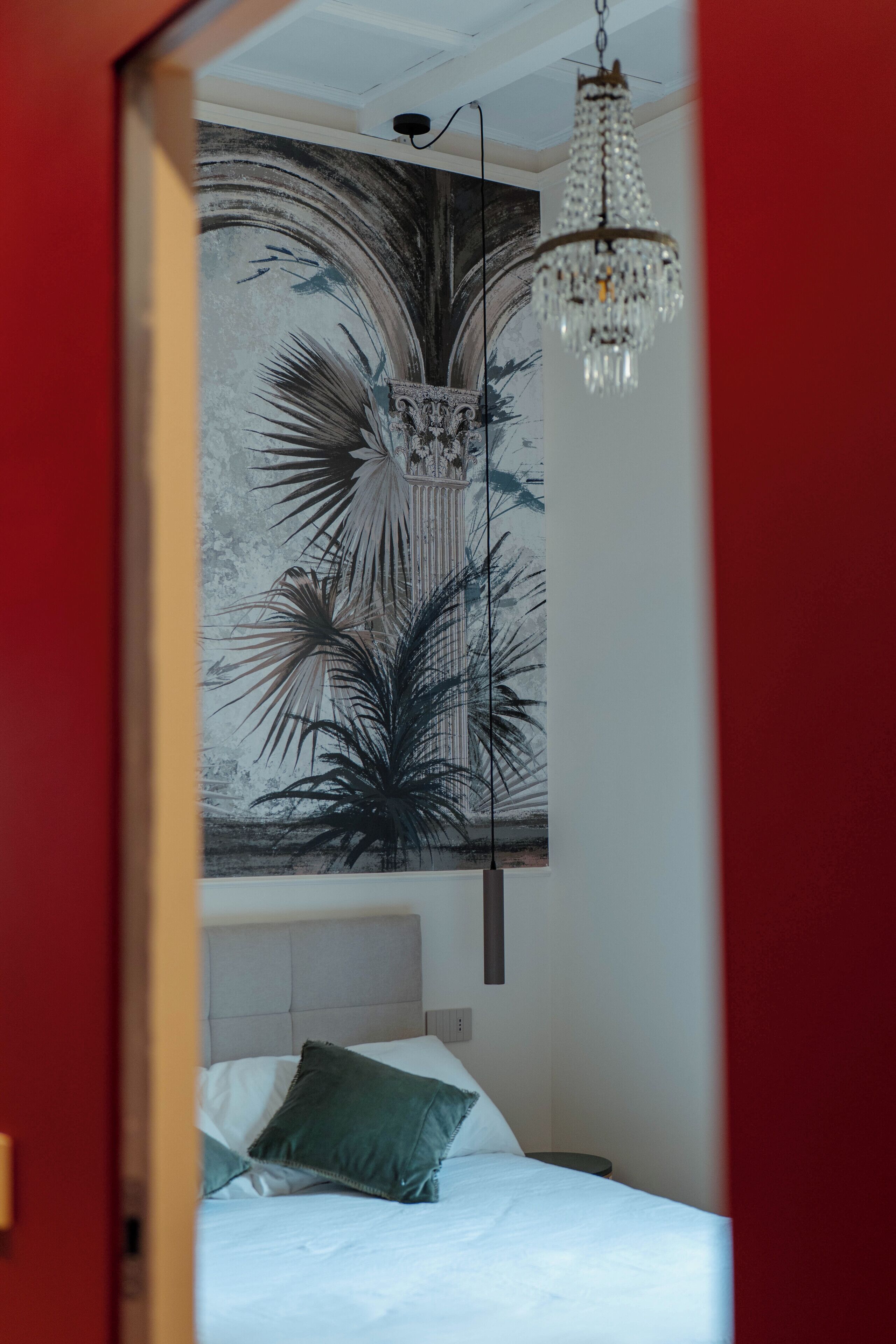 Habitació amb un llit, un quadre penjat a la paret i un penjall.