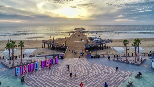 A beach with a pier, a sign reading 'PISMO BEACH', and people walking. - NEW LISTING - Coastal Pismo Escape • Steps to Beach & Downtown • 2 Car Garage (Pismo Beach)