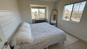 A bedroom with a bed, a window, a mirror, and a view of the outside. - NEW LISTING - Coastal Pismo Escape • Steps to Beach & Downtown • 2 Car Garage (Pismo Beach)