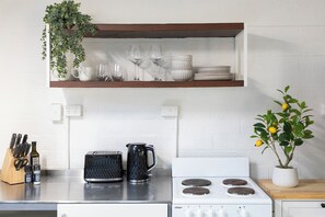 A kitchen with a white stove, a black coffee maker, and a plant with yellow flowers.