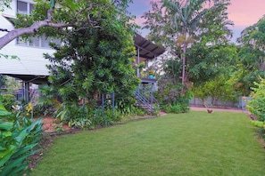 A backyard with a lawn, a covered patio, and various plants.