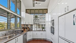 A modern kitchen with white cabinetry, stainless steel appliances, and a wooden floor.