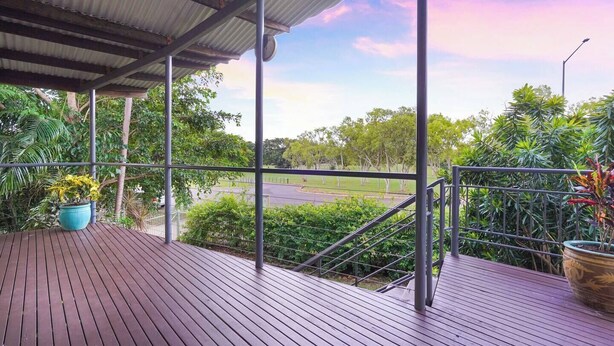 A covered outdoor area with a view of a road and greenery.