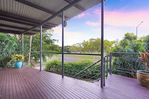 A covered outdoor area with a view of a road and greenery.