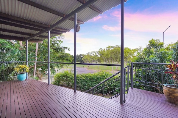 A covered outdoor area with a view of a road and greenery.