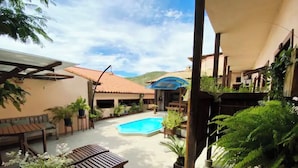 A pool area with a wooden deck, lounge chairs, and potted plants. - Flamboyant Space - Armação dos Búzios - Summer House Near the Beach (Armação dos Búzios)