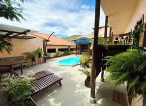A pool area with a wooden deck, lounge chairs, and potted plants. - Flamboyant Space - Armação dos Búzios - Summer House Near the Beach (Armação dos Búzios)