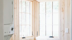 A corner laundry room with wooden walls, a window, and a built-in shelf with baskets. - The Doctor's Cottage -- 1 mile from Prisma Hospital, 2 miles from Downtown GVL (Greenville)