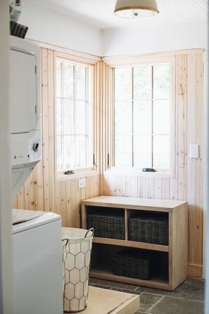 A corner laundry room with wooden walls, a window, and a built-in shelf with baskets. - The Doctor's Cottage -- 1 mile from Prisma Hospital, 2 miles from Downtown GVL (Greenville)