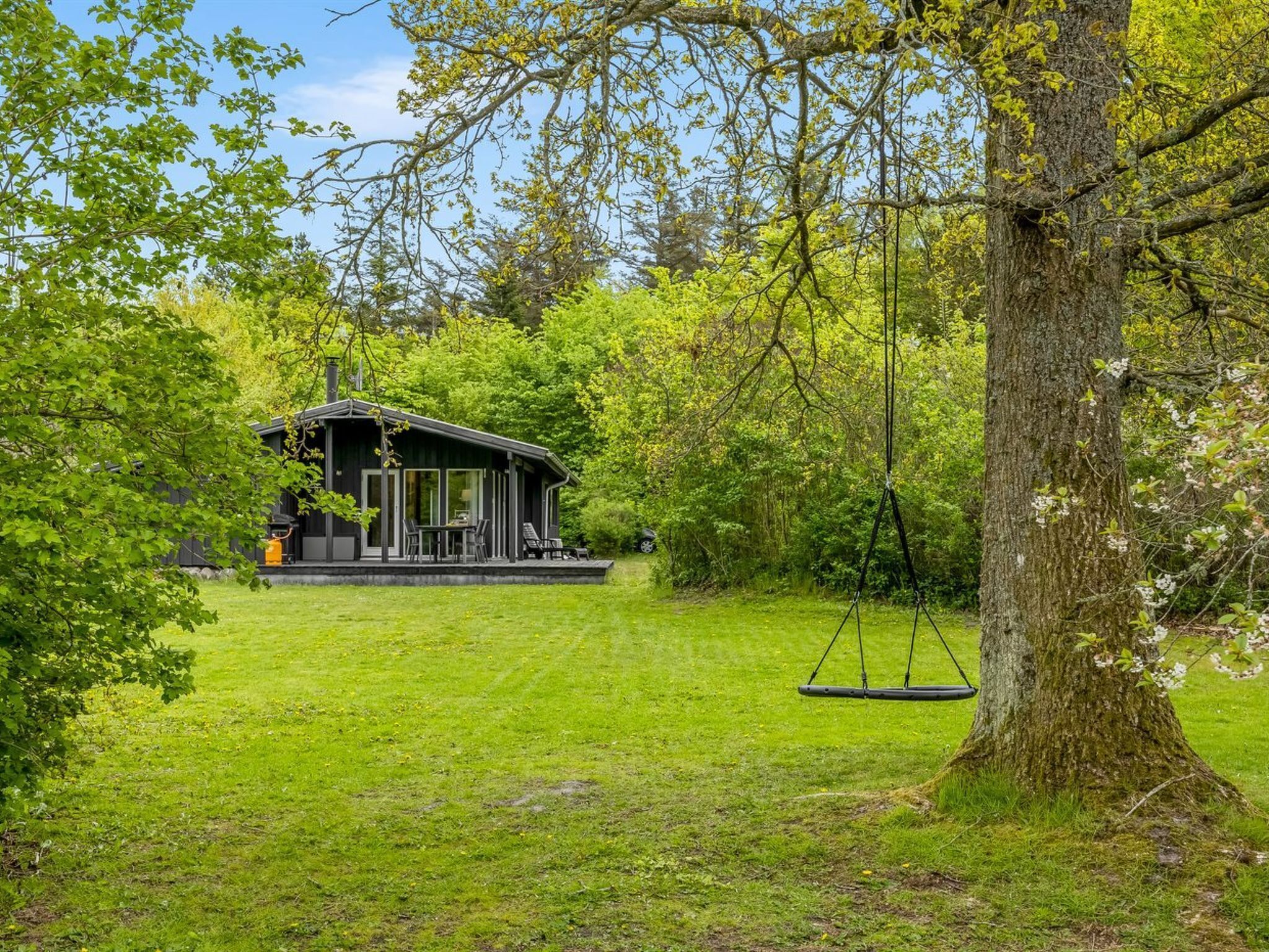Eine Hütte mit Veranda, umgeben von üppiger Vegetation und einer Schaukel.