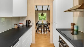 A modern kitchen with wooden walls, a dining area with a table and chairs, and a view through a window. - "Julika" - 560m from the sea by Interhome (Sæby)