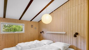 A room with a bed, a window, a wooden ceiling, and a hanging light fixture. - "Julika" - 560m from the sea by Interhome (Sæby)