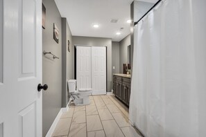 Un baño con inodoro, un armario y cortina de ducha.