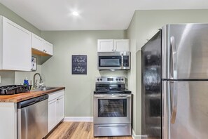 A kitchen with white cabinets, a stainless steel refrigerator, a microwave, and an oven. - Bethany Grove House B | Cozy Three Bedroom Stay (Huntsville)