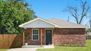 A single-story brick house with a front door, a small porch, and a visible garage door. - Cozy Coastal House Near Fishing, Bay Views (Palacios)