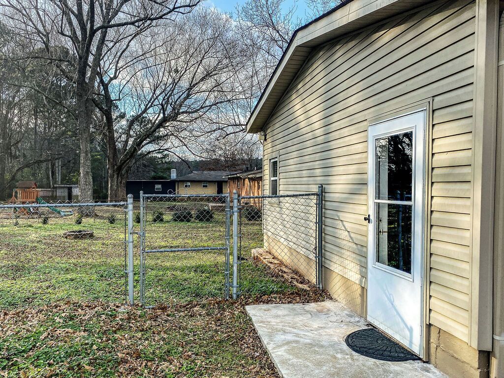 A single-story house with a front door, a small porch, and a fenced yard.