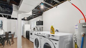 A modern kitchen with built-in appliances, a dining area, and a laundry room with washing machines.