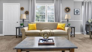 A living room with a sofa, coffee table, lamps, and decorative items.