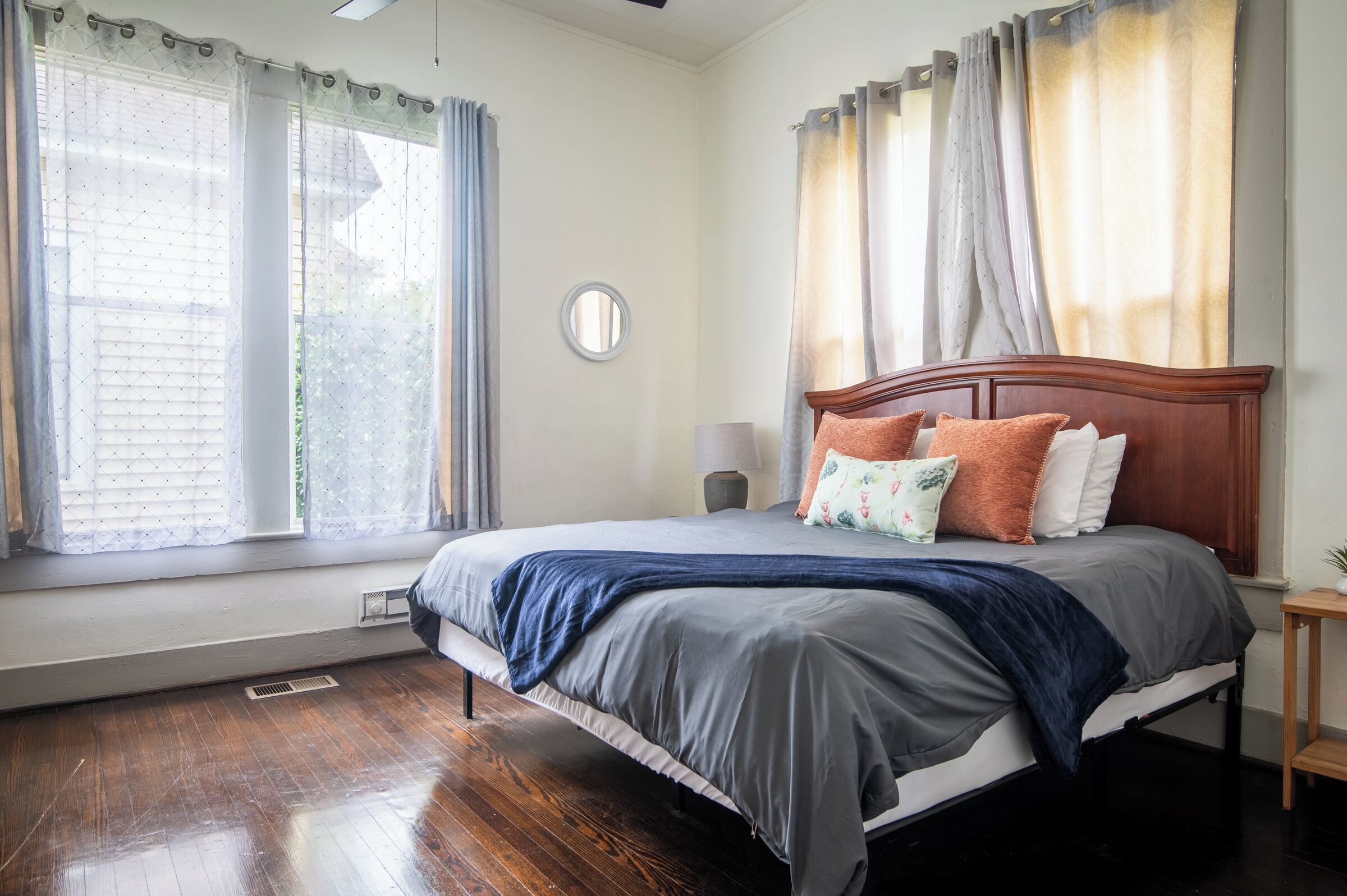 Un dormitorio con cama de madera, mesita de noche, lámpara y ventana con cortinas.