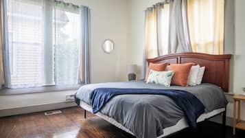 Un dormitorio con cama de madera, mesita de noche, lámpara y ventana con cortinas.