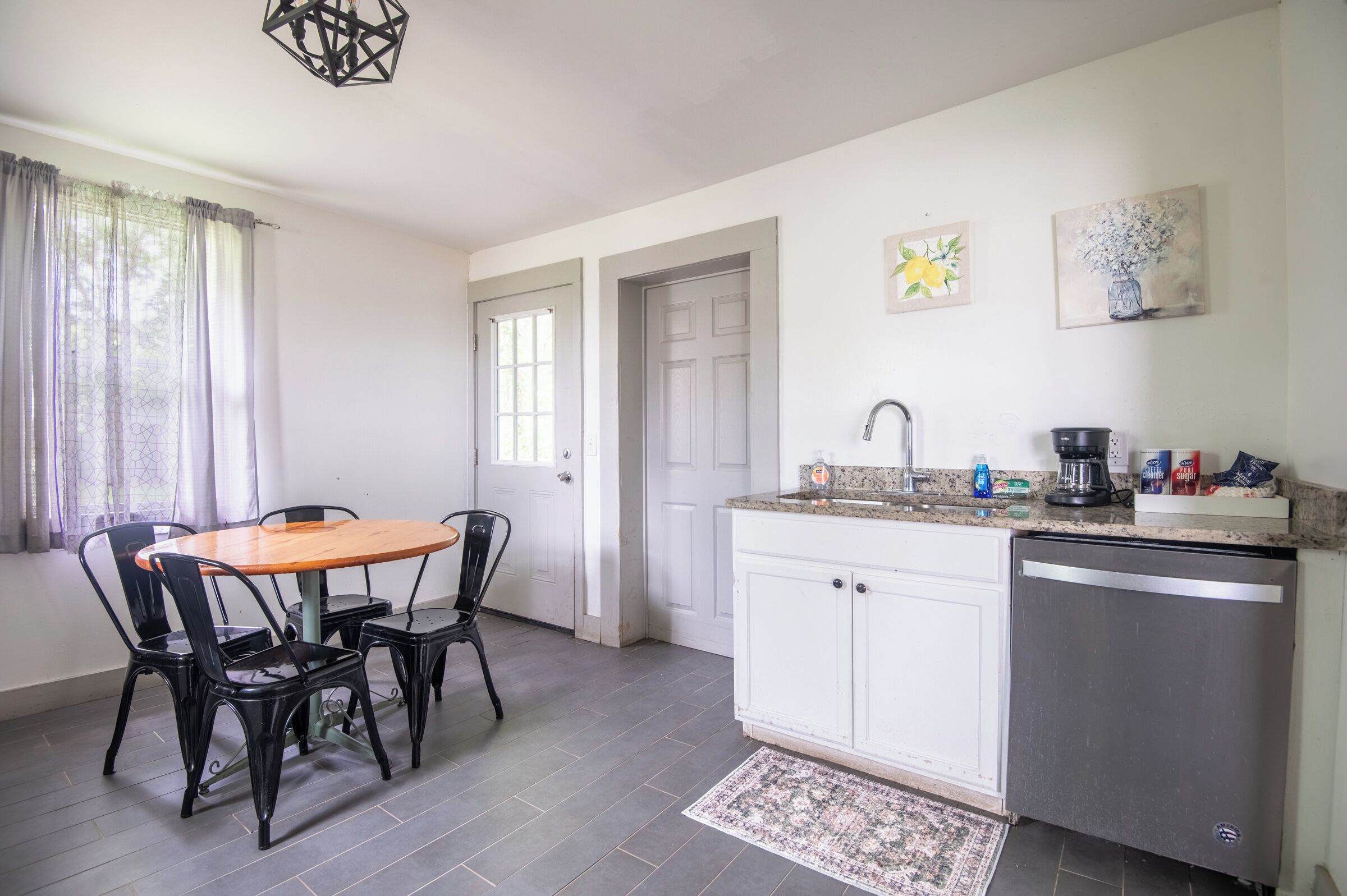 A kitchen with a dining table and chairs, a refrigerator, and a coffee maker.
