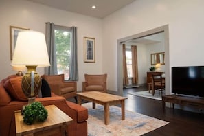 A living room with a sofa, armchair, coffee table, TV, and a lamp.