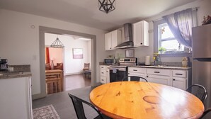 Una cocina moderna con armarios blancos, una campana extractora de acero inoxidable y un microondas integrado.