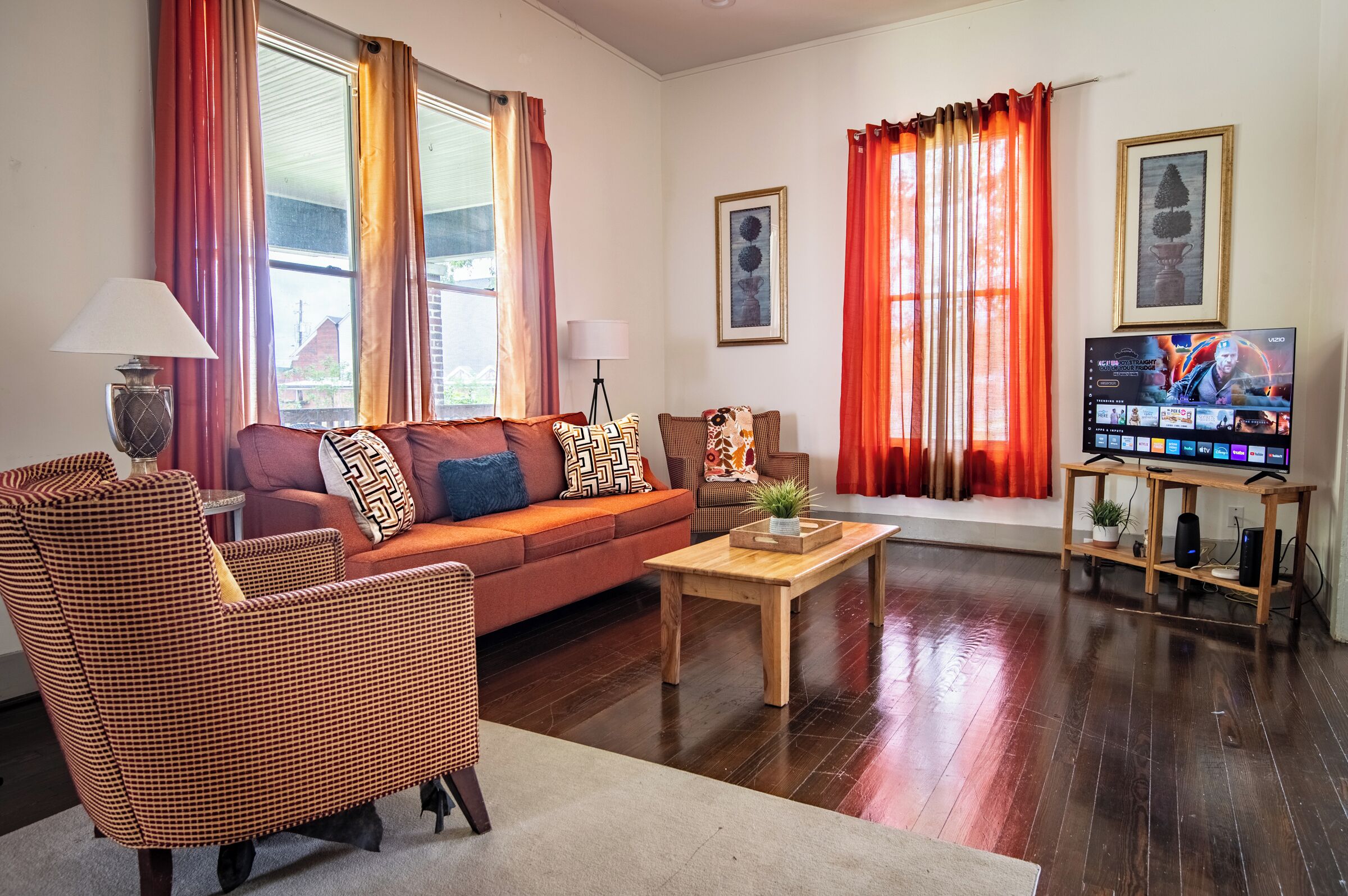 A living room with a sofa, armchairs, a coffee table, and a TV on a wooden stand.