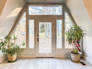 A door with a view of a driveway and trees, two potted plants, and a tiled floor. - Dome House on Bell | Group Stay Near Research Park (Huntsville)