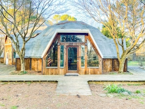 A wooden cabin with a large glass door, a wooden deck, and a metal roof. - Dome House on Bell | Group Stay Near Research Park (Huntsville)