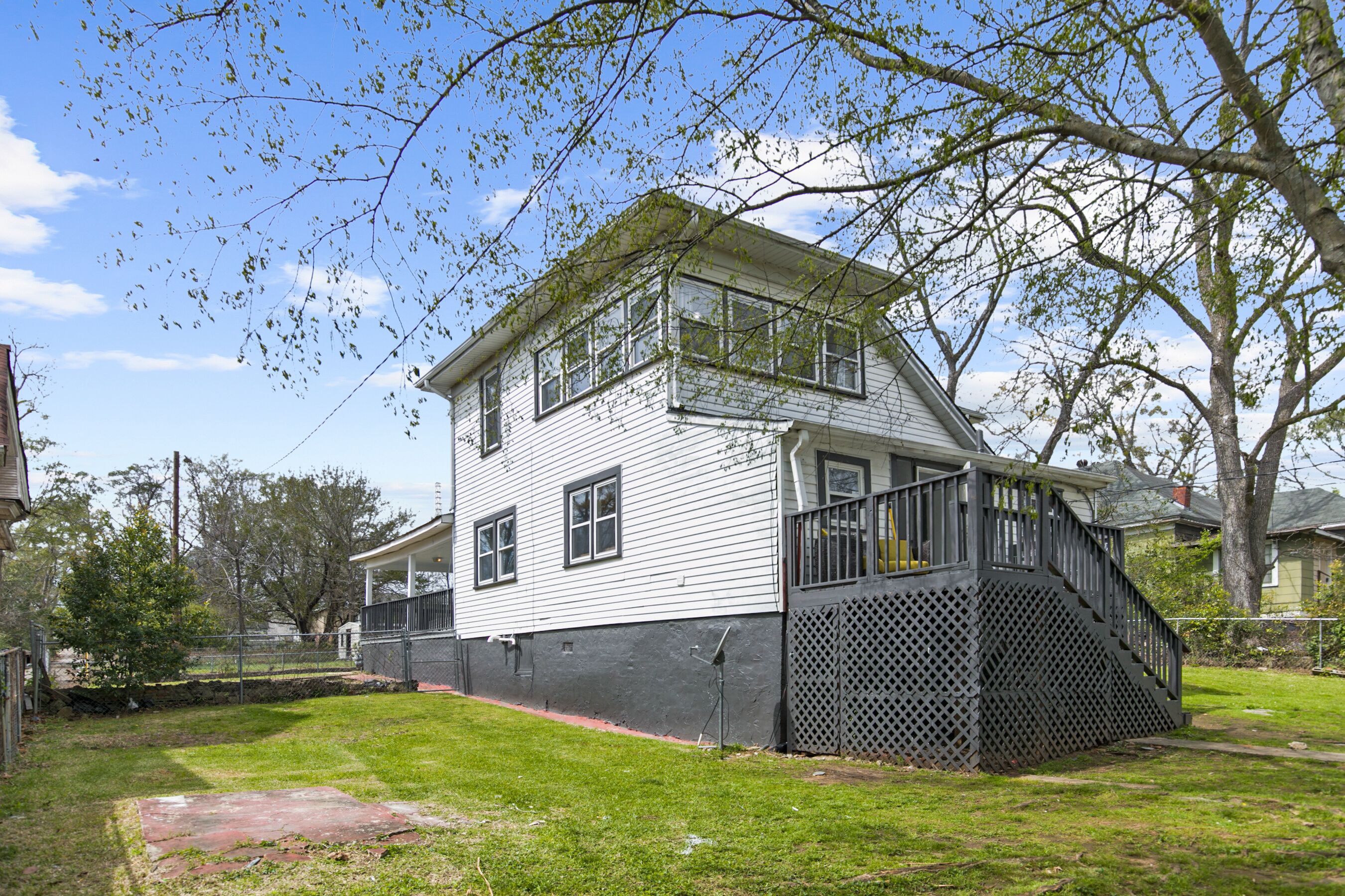 A two-story house with a covered porch and a fenced yard.